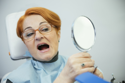 woman looks at teeth in the mirror